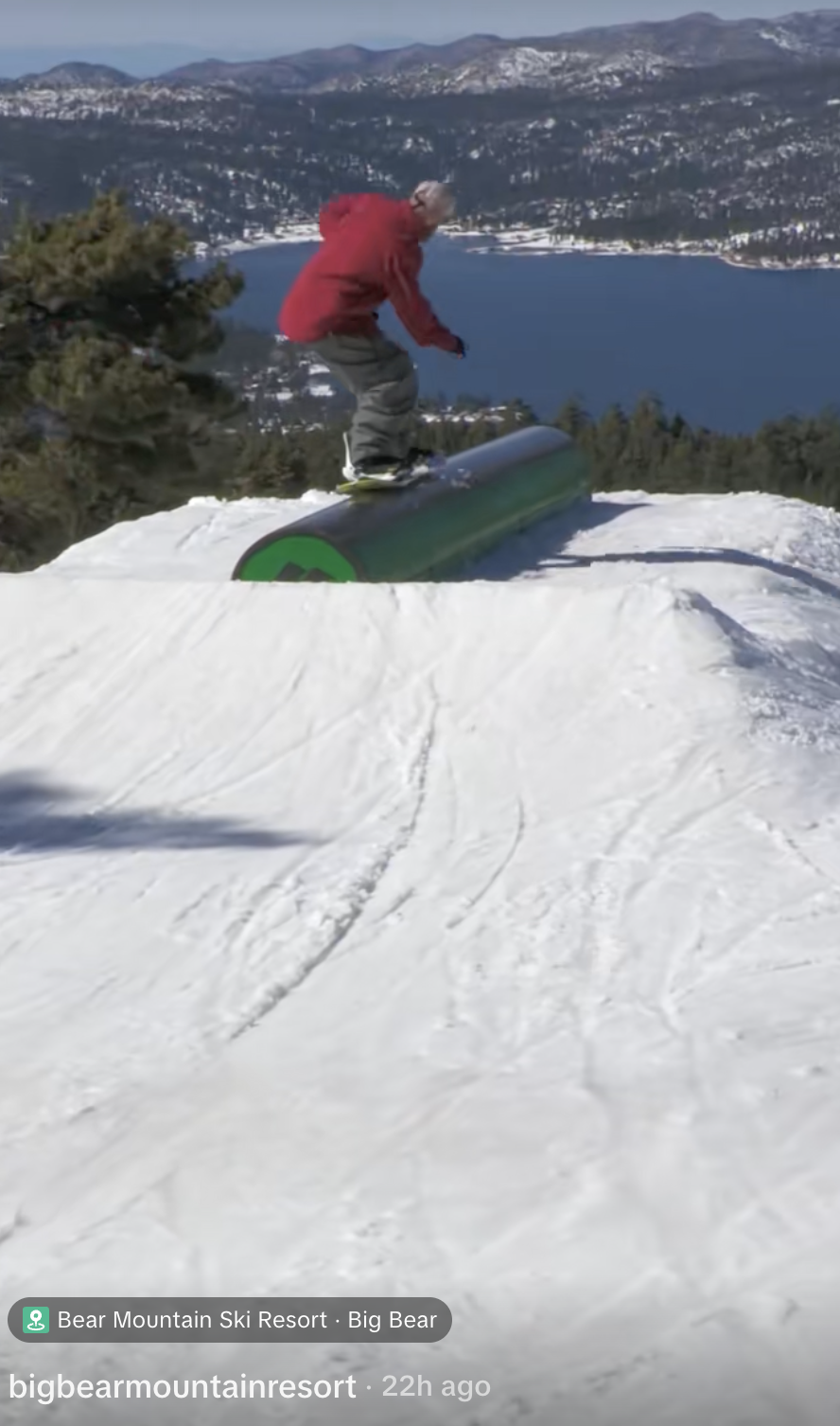 A snowboarder in red long sleeve siding on a green tube with Big Bear Lake in the distance on the most recent Big Bear Mountain Resort Tik Tok video.